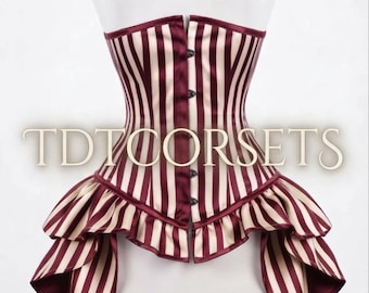 May include: A strapless corset featuring vertical burgundy and cream stripes. The garment has a front button closure and a layered, ruffled peplum hem that extends longer at the sides. The text TDTCORSETS is overlaid across the center of the corset.