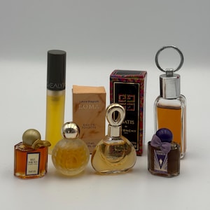 May include: A collection of eight miniature perfume bottles and two boxes. The items include White Diamonds, Calyx, Laura Biagiotti Roma, Givenchy Ysatis, Van Cleef & Arpels First, and Giorgio Passion. The bottles vary in shape, size, and color, featuring gold, silver, and purple caps, with amber and clear liquid contents.