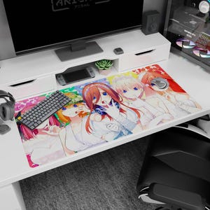 Könnte beinhalten: Eine rechteckige Schreibtischunterlage mit einer farbenfrohen Anime-Illustration von fünf Charakteren mit unterschiedlichen Haarfarben, darunter Rot, Pink und Orange, die weiße Outfits tragen. Die Unterlage liegt auf einem weißen Schreibtisch.