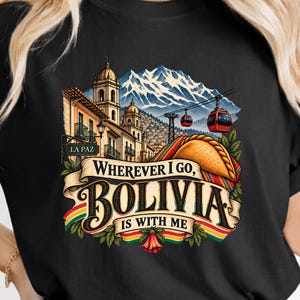 Puede incluir: Una camiseta negra con un estampado gráfico de La Paz, Bolivia, que muestra montañas nevadas, teleféricos rojos, una salteña y una pancarta que dice "WHEREVER I GO, BOLIVIA IS WITH ME" en letras negras con detalles en rojo, amarillo y verde.