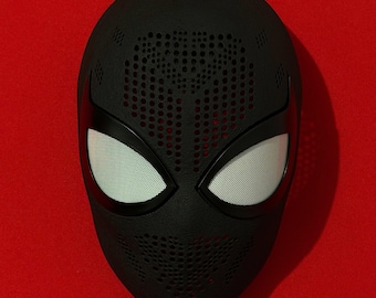 May include: A matte black full-face mask featuring a textured surface with a perforated dot pattern across the forehead and chin areas. The mask includes two large, almond-shaped eye openings covered with a fine, light-colored mesh material.