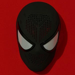 May include: A matte black full-face mask featuring a textured surface with a perforated pattern across the forehead and chin areas. The mask includes two large, almond-shaped eye openings covered with a fine white mesh material.
