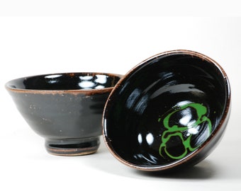 Stoneware soup bowls glazed in black Tenmoku glaze with green decoration in each one