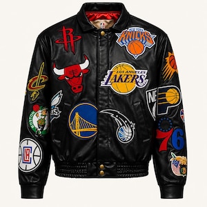 Puede incluir: Una chaqueta universitaria de cuero negro con varios logotipos y parches coloridos de equipos de la NBA en la parte delantera y las mangas. La chaqueta tiene un cuello clásico, cierres de botones a presión, puños y dobladillo acanalados y un forro interior rojo y beige.