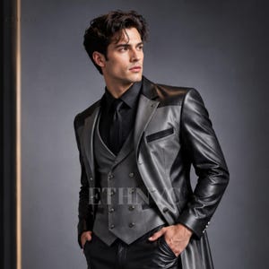May include: A long-sleeved black and grey leather blazer featuring a double-breasted waistcoat with metallic buttons, a black collared shirt, and a black tie. The garment displays a two-tone colour scheme with black sleeves and lapels.