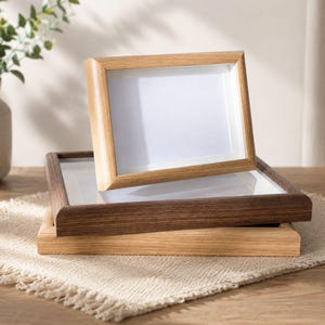 Peut inclure: Trois cadres photo rectangulaires empilés les uns sur les autres. Le cadre supérieur est en bois clair, le cadre central est en bois brun foncé et le cadre inférieur est en bois clair. Chaque cadre possède un passe-partout blanc et une vitre.