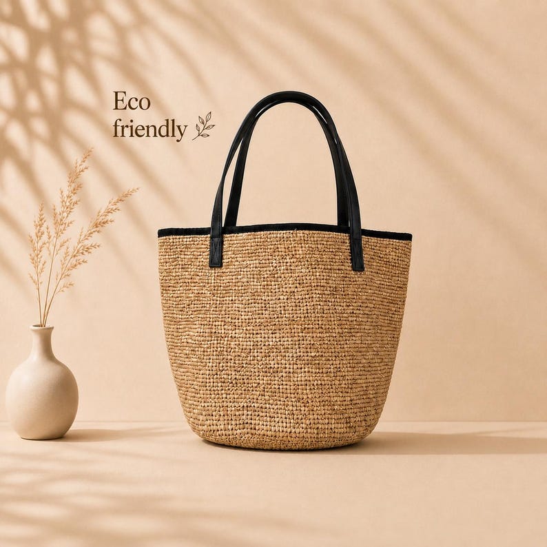 Pu&ograve; includere: Una borsa tote in paglia intrecciata con base arrotondata e due manici neri in similpelle. Il bordo superiore &egrave; rifinito in nero. Il testo Eco friendly &egrave; stampato sul lato sinistro con una piccola icona a forma di foglia. Texture beige naturale.