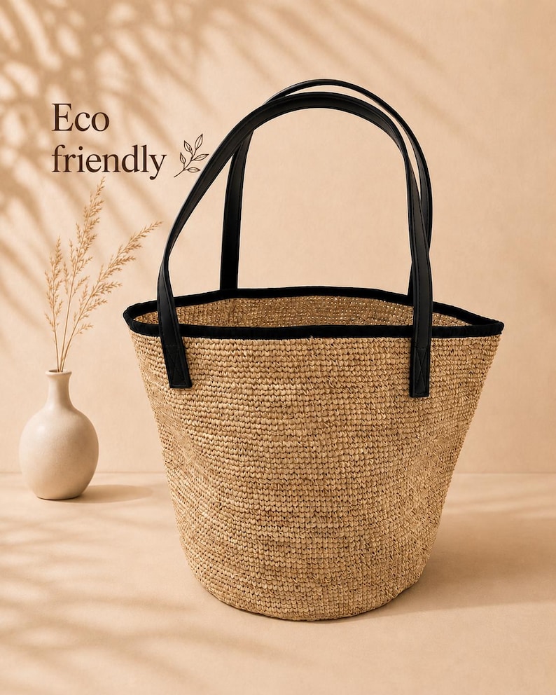 Pu&ograve; includere: Una borsa tote in paglia intrecciata con un'apertura ampia e un bordo nero lungo il margine superiore. La borsa presenta due manici neri e include la scritta Eco friendly stampata sul lato. Il corpo della borsa ha una finitura naturale beige.