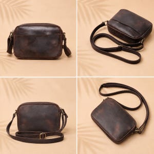 May include: A dark brown rectangular crossbody bag with a smooth finish, featuring a top zipper closure, a long adjustable shoulder strap with a metal buckle, and antique brass-toned hardware attachments on the sides of the bag.