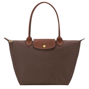 May include: A brown tote bag featuring a smooth, solid-colored body with a trapezoidal shape. It includes two long, thin brown leather handles, a top zipper closure with a gold-toned pull, and a brown leather flap with a gold-toned snap button.