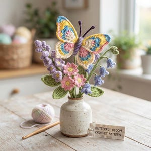 May include: A crochet butterfly and flower bouquet in a speckled ceramic vase. The butterfly features yellow, blue, and pink yarn. The bouquet includes purple and pink flowers with green leaves. A tag reads BUTTERFLY BLOOM CROCHET PATTERN.