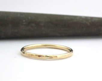 May include: A simple, hammered gold band ring.