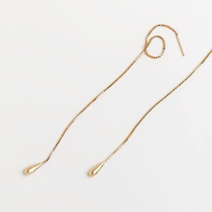 May include: A pair of gold teardrop earrings with delicate chain drop designs.