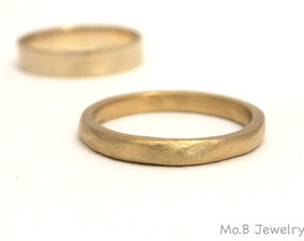 May include: Two gold wedding bands, one is a simple band and the other is a thicker band with a slightly rounded edge.