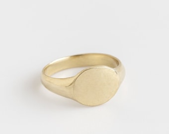 May include: A gold signet ring with a smooth, oval-shaped top.