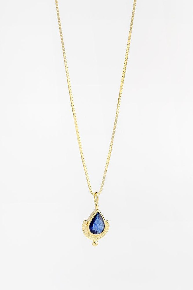 May include: A gold chain necklace with a teardrop-shaped pendant featuring a blue gemstone set in a gold frame.