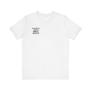 Peut inclure: Un t-shirt blanc à manches courtes avec un texte noir sur la poitrine gauche indiquant : MY BACKTEST HAD A 94% WIN RATE, accompagné d'un petit graphique en forme de flèche pointant vers le haut à côté du symbole de pourcentage.