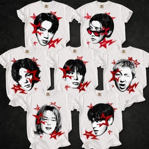 Op de afbeelding: Zeven witte t-shirts in een groep gerangschikt, elk met een zwart-wit portret van een ander persoon. Elk shirt is versierd met meerdere rode stergraphics van verschillende groottes die rondom het centrale portret zijn verspreid.