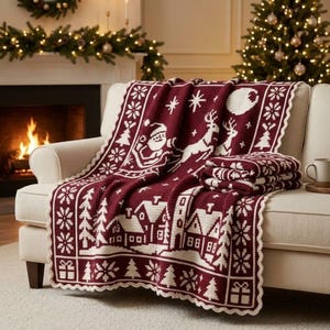 Può includere: Una coperta in maglia rosso scuro e bianca con un motivo natalizio ripetuto raffigurante Babbo Natale su una slitta, renne, case innevate, alberi di pino, fiocchi di neve e pacchi regalo, rifinita con un bordo smerlato all'uncinetto bianco.