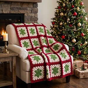 May include: A handmade crochet blanket featuring a repeating granny square pattern. Each square consists of a central green snowflake motif surrounded by cream-colored yarn, all bordered by a deep red yarn that connects the individual squares.