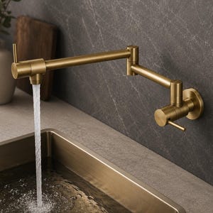 May include: A wall-mounted pot filler faucet with a brushed brass finish and a double-jointed swing arm. The faucet features two cylindrical handles for water control and is shown dispensing a steady stream of water into a kitchen sink.