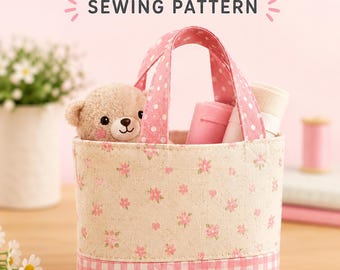 May include: A mini tote bag sewing pattern featuring a beige fabric with a small pink floral print and a pink and white gingham base. The bag has pink polka dot handles and contains a small plush bear and rolled fabric pieces.
