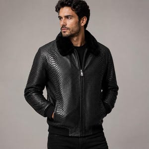 May include: A black jacket featuring a textured snakeskin-like pattern, a full-length front zipper, and a plush black faux fur collar. The garment includes ribbed black cuffs and a ribbed hem, providing a structured fit with long sleeves.