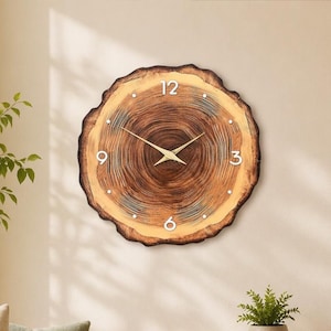 May include: A round wall clock crafted from a natural wood slice featuring a prominent dark brown centre with lighter tan outer rings. The clock face displays white numerals at the 12, 3, 6, and 9 positions, with thin gold-coloured hands at the centre.
