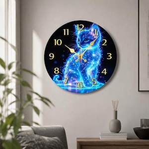 May include: A round wall clock featuring a glowing blue kitten illustration against a dark background. The clock face displays gold-coloured numerals from one to twelve and matching gold-coloured hour, minute, and second hands centred on the image.