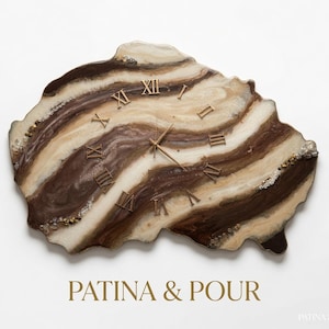 May include: An irregular, geode-style wall clock featuring swirling bands of dark brown, cream, and white resin. The clock face displays gold Roman numerals and thin gold hands. The text PATINA & POUR is printed in gold below the clock.
