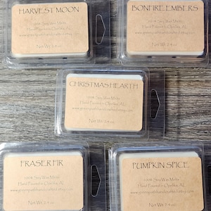 May include: Five small, clear plastic containers with brown paper labels. Each container holds a white wax melt. The labels have the names of the scents: Harvest Moon, Bonfire Embers, Christmas Hearth, Fraser Fir, and Pumpkin Spice. Each label also includes the text "100% Soy Wax Melts", "Hand Poured in Opelika, AL", "www.greenpathhandcrafted.etsy.com", and "Net Wt. 2.4 oz".