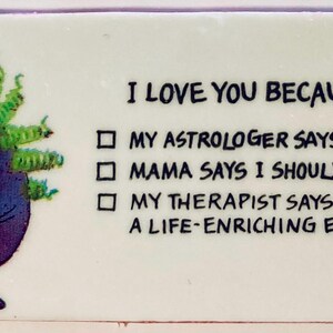 May include: A rectangular white sticker with the text "I LOVE YOU BECAUSE" and three bullet points. A cartoon character with purple skin and green hair is on the left side.