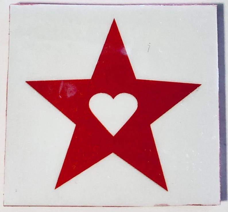May include: A square, white background with a red star design. Inside the red star is a white heart shape. The edges of the square have a thin red border.