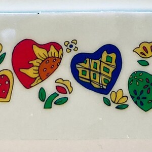 May include: A rectangular decorative piece featuring colorful heart and flower designs. The hearts are red, blue, green, and yellow, with various patterns and embellishments. Flowers and leaves are also included in the design.