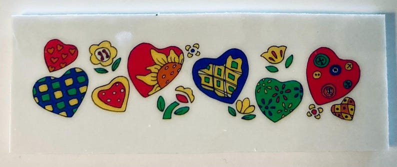 May include: A rectangular decorative piece featuring colorful heart and flower designs. The hearts are red, blue, green, and yellow, with various patterns and embellishments. Flowers and leaves are also included in the design.
