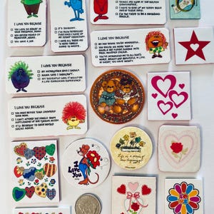 May include: A collection of small, decorative items with various designs and text. The items include cartoon characters, hearts, and the phrase "I Love You Because." Colors include red, blue, green, and yellow. Some items are square, round, or rectangular.