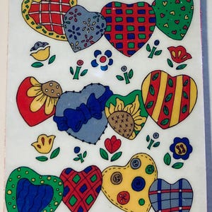 May include: A decorative sheet of colorful heart-shaped stickers. Each heart features a unique pattern, including plaid, floral, and button designs. The stickers are in various colors, such as red, blue, green, and yellow, with floral and botanical accents.