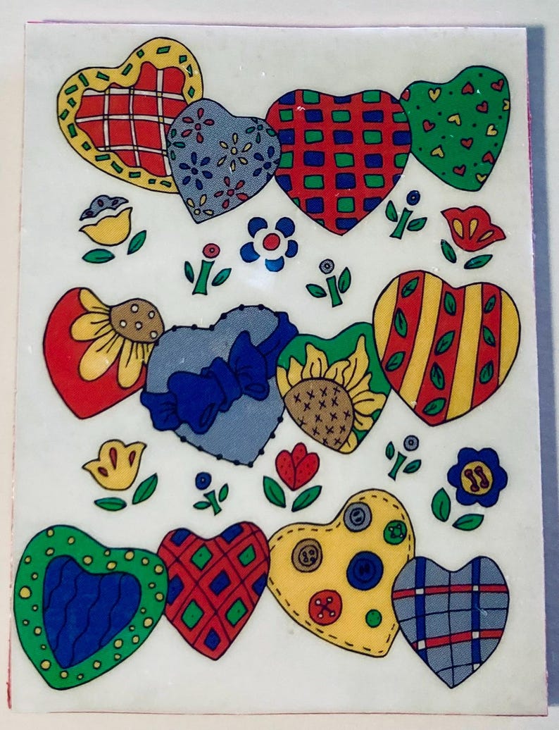 May include: A decorative sheet of colorful heart-shaped stickers. Each heart features a unique pattern, including plaid, floral, and button designs. The stickers are in various colors, such as red, blue, green, and yellow, with floral and botanical accents.