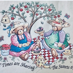 Puede incluir: Dos osos de peluche con sombreros y vestidos están teniendo un picnic bajo un árbol con manzanas rojas. Los osos están sentados en una manta a cuadros rojos y blancos con una tetera, un tarro de miel y un plato de galletas. El texto "Good Times are Sharing The Sweets of Life" está escrito debajo de los osos.