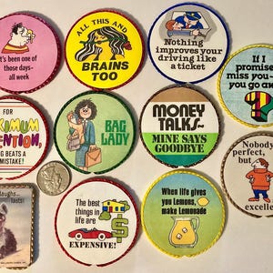 May include: A collection of ten circular and one rectangular pinback buttons featuring various colorful illustrations and humorous text, including phrases like Money Talks, Bag Lady, and All This and Brains Too, displayed alongside a US quarter coin.
