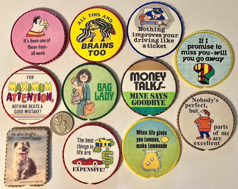 May include: A collection of ten circular and one rectangular pinback buttons featuring various colorful illustrations and humorous text, including phrases like Money Talks, Bag Lady, and All This and Brains Too, displayed alongside a US quarter coin.