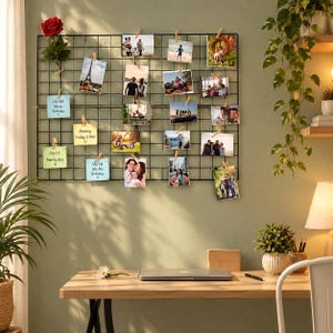May include: A black metal wire grid wall organizer featuring multiple rectangular sections. The grid is adorned with various photographs, a single red rose, and several light blue and yellow paper notes with handwritten text attached by clips.