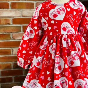 May include: Red dress with a white lace trim and a pattern of owls and hearts. The dress has the text "Owl Be Yours" repeated on it.