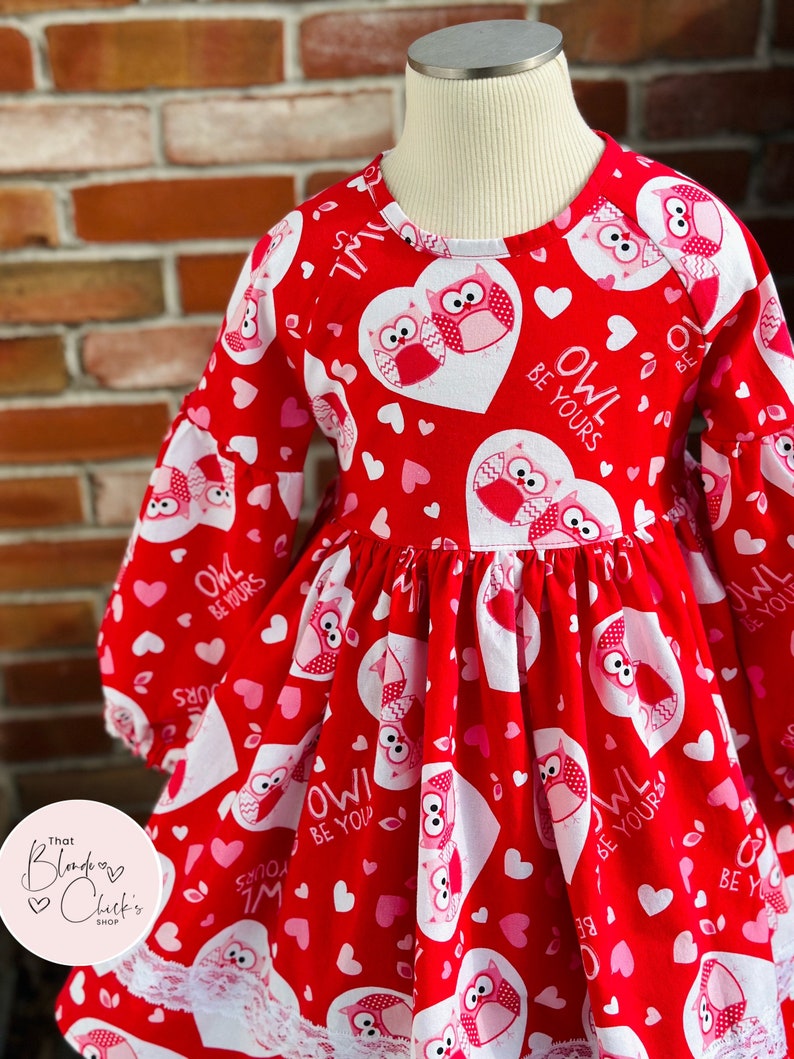May include: Red long-sleeved dress with a white lace trim. The dress features a heart and owl pattern with the text "Owl Be Yours".