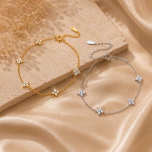 Peut inclure: Deux bracelets à chaîne délicats, l'un doré et l'autre argenté, chacun orné de quatre breloques en forme de fleur régulièrement espacées et serties de petites pierres claires. Les deux bracelets ont une fine chaîne et un fermoir circulaire.