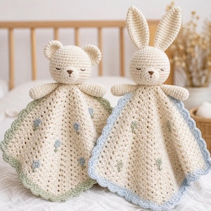 Può includere: Due doudou all'uncinetto a forma di orsetto e coniglietto. Entrambi hanno il corpo color crema con piccoli ricami floreali blu e verdi, bordi smerlati in verde salvia e azzurro, e occhi chiusi ricamati con nasi di colore marrone.