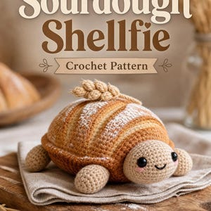Könnte beinhalten: Eine Häkelanleitung mit dem Titel Sourdough Shellfie, die ein schildkrötenförmiges Amigurumi mit einem braunen, brotähnlichen Panzer zeigt, der mit einem Weizenhalm verziert ist. Die Schildkröte hat einen hellbeigen Kopf, Gliedmaßen und ein Gesicht.