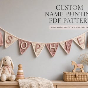 May include: A crochet bunting banner featuring triangular flags in cream and dusty rose, spelling the name SOPHIE with raised letters. The banner includes two matching tassels at the ends. Text reads: CUSTOM NAME BUNTING PDF PATTERN BEGINNER EDITION - A-Z GUIDE.