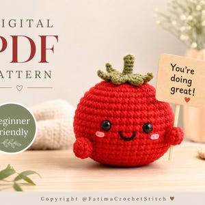 Op de afbeelding: Een rode gehaakte tomaat amigurumi met een groene steel, zwarte veiligheidsoogjes, een geborduurde glimlach en roze wangen. Het houdt een klein beige bordje vast met de tekst You're doing great! en een rood hartje. Tekst: DIGITAL PDF PATTERN.