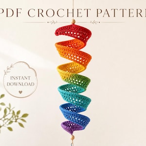 May include: A spiral-shaped crochet hanging decoration featuring a vibrant rainbow color gradient from red to purple. The text PDF CROCHET PATTERN and INSTANT DOWNLOAD are visible. The structure is suspended by a string with small wooden beads.